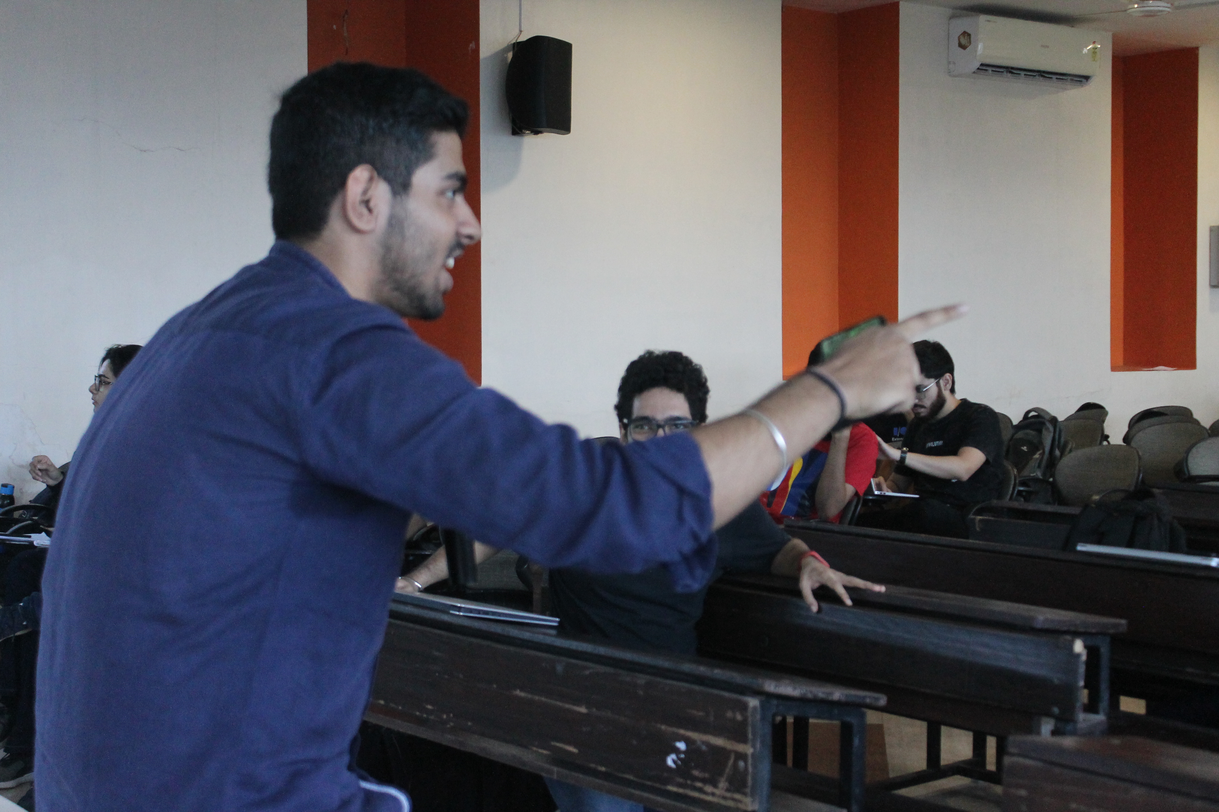 A picture of Tushar Nankani holding a mic with his back visibile and pointing at the audience holding a mic.